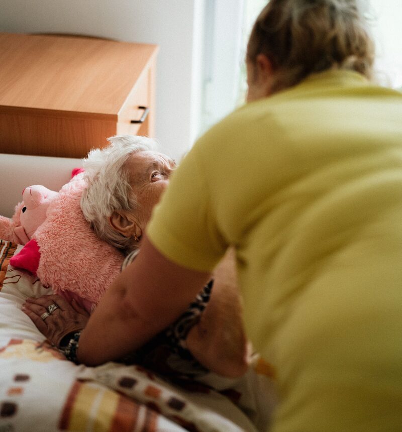 Pflegerin reicht einer älteren Frau zu Hause die Hand